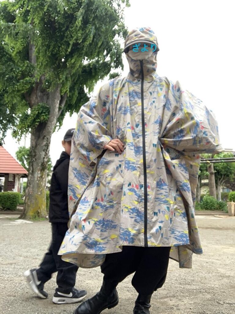 レインポンチョを着て直立する女の人