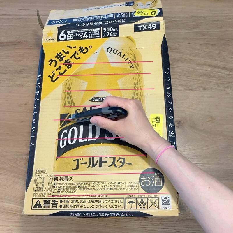 段ボール箱に横の切り込みをカッターナイフで数本入れている