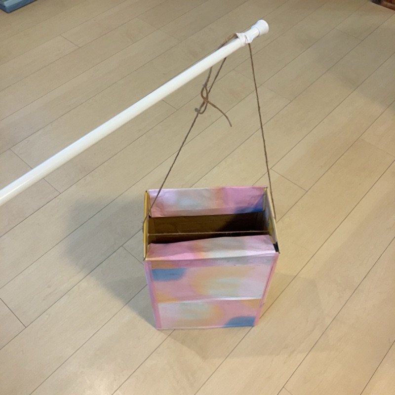 突っ張り棒にお菓子の入った箱をぶら下げている